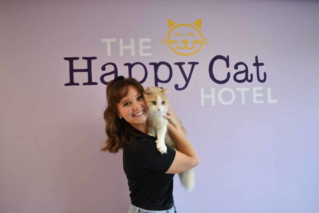 Happy Cat Hotel staff with cat and logo